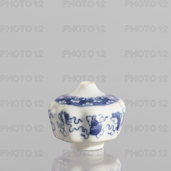 Small spice vessel, blue-and-white porcelain, 19th century China. No stopper. Height 4.6 cm; diameter 5.5 cm. Decorated with baigu ornament., A small white porcelain object with a rounded, slightly lobed body and a narrow top opening sits against a neutral gray background, decorated with a pattern in blue featuring flowing, cloudlike motifs and a band of floral shapes near the top; the surface is glossy and the piece rests on a short foot, with reflections visible beneath it.