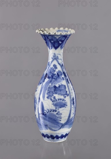 Vase, ceramics; blue-and-white porcelain; Japanese, 19th/20th century; Japanese art; plant ornament decoration; vessel; height 36.6 cm; diameter 14 cm., A slender ceramic vase with a flared, ruffled rim sits against a plain background, painted in a blue-and-white palette; the body shows flowing brushwork forming floral and foliate motifs in various shades of blue on a white ground, with darker blue accents near the neck and base and softer blue washes across the bulbous midsection, and the surface has a glossy finish that reflects light.
