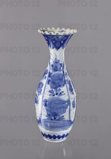 Vase, ceramics, blue and white porcelain, Japanese, 19th/20th century Japan, plant ornaments, vessel, height 36.6 cm, diameter 14 cm, A ceramic vase stands against a plain gray background; the vase has a narrow neck flaring into a ruffled rim and a bulbous body tapering to a small base, decorated with blue painted floral and abstract motifs on a white ground, showing brushstroke textures and areas of darker and lighter blue, with the rim edge appearing off-white and the overall color palette including blue, white, gray, and a touch of beige.