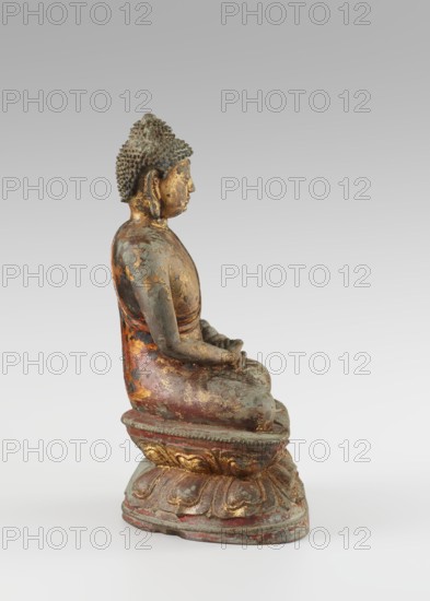 Buddha, 18th century ; Chinese, Qing 1644–1911; Buddhist art—Chinese Buddhism; sculpture/figurine of Buddha with ushnisha on a lotus throne; height 25.5 cm, width 16.0 cm., A seated statue of a figure shown in profile on a decorative base, with a textured hair or headpiece, closed eyes and a calm facial expression, hands resting in the lap, wearing a robe that shows worn and flaking surfaces; the surface displays a mix of colors including gold, greenish patina, reddish-brown, and areas of dark gray, with the base featuring ornamental carved forms highlighted in gold and red.