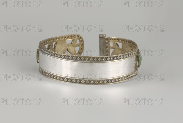 Headband, plant ornament, Chinese culture, Chinese art, Qing 1644–1911, head ornament, openwork inlaid with glass, semi-precious stones, river pearls and beads, 19th century, China, height 3.3 cm, diameter 12 cm., A metallic cuff with a polished silver band flanked by decorative gold-toned borders rests on a pale gray surface against a light gray background; the cuff has ornate pierced gold-toned interior details visible at the open ends and a small green stone set into each side, with the overall colors being silver, gold, green, and shades of gray.