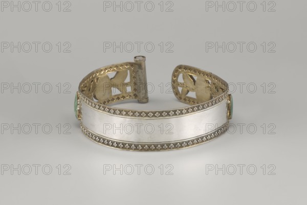 Headband, plant ornament, Chinese, Chinese art, Qing 1644–1911, head ornament, openwork inlaid with glass, semi-precious stones, river pearls and beads, 19th century, China, height 3.3 cm, diameter 12 cm, A metal cuff bracelet displayed against a gray background, featuring a central smooth silver-colored band bordered by decorative gold-colored trim with a repeating floral motif; the interior and ends of the cuff show gold-colored cutoutwork with geometric and curved shapes, and small green-colored stone settings are visible at the sides.