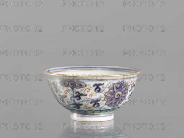 Bowl, Chinese art, Chinese culture, Qing dynasty 1644–1911, 19th century, ceramics, colored porcelain, plant and floral ornaments including lotuses and lotus tendril ornament, floral motifs on the reverse of the rim, vessel, diameter 6.8 cm, A small porcelain bowl with a rounded shape and a narrow foot sits against a plain gray background, decorated with an intricate floral and cloudlike pattern in blue, purple, green, pale yellow, orange, and red, with gold trim along the rim and foot, and a white interior and base visible.