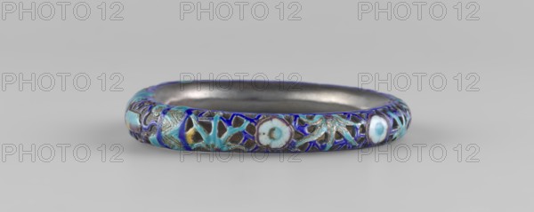 Bracelet, ; ornaments, Chinese art, Chinese culture; women's ornament; Qing dynasty 1644–1911, 19th century; hundred antiquities baigu ornament; jewelry; diameter 11.0 cm., A circular metal bangle with a dark inner surface and an outer surface decorated with cloisonné-style enamel featuring a pattern of floral and foliate shapes in shades of blue, turquoise, white, and touches of yellow set against dark metal outlines; the bangle sits on a smooth light gray background and is shown in a low-angle side view.