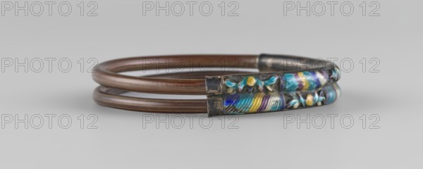 Bracelet, ornaments, Chinese art, Chinese culture, women's ornaments, Qing 1644–1911, plant ornament, enamel colors: white, yellow, teal, blue, 19th century, China, jewelry, diameter 7.0 cm, A coiled circular bracelet composed of two smooth brown metal bands joined at one end by a decorative rectangular segment that features raised floral and feather-like patterns in blue, turquoise, purple, yellow, and silver tones, with the decorative metal showing darker, tarnished areas; the background is a smooth pale gray.