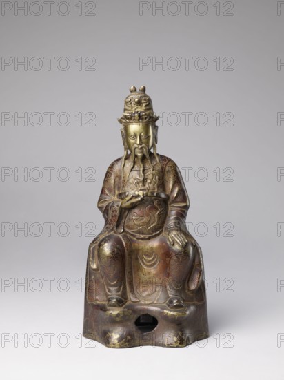 Mythical emperor, gift, Chinese art, Chinese culture, Qing 1644–1911, Qing style, figurine of a ruler wearing a dragon robe with dragon iconography, 19th century, China, sculpture; height 41.0 cm, A seated statue of a bearded figure wearing a tall ornate headdress and long flowing robes, rendered in metallic tones of gold, bronze, and brown with areas of darker patina; the figure has a long mustache and beard and holds an object in one hand while the other rests on the knee; the robes display engraved decorative patterns and wave-like motifs, and the base has a rounded opening and shows worn gold highlights and darker brown wear; the background is a smooth, neutral gray.