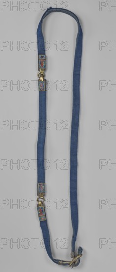 Bridle reins bridle fragment, maker, Chinese; Qing dynasty 1644–1911; cloisonné enamel on copper with leather ribbon and bronze; decoration includes fish motifs; horse tack riding equipment, length 86 cm; 18th century., A long narrow fabric strap in blue arranged in a loop with frayed ends and visible stitching, featuring several small rectangular metal fittings with colorful enamel inlays showing abstract multicolored motifs in shades of red, green, pink, purple, blue, yellow, and white; the fittings are attached with brass-toned rings and clasps that show a warm metallic color, and the overall background is a neutral light gray.