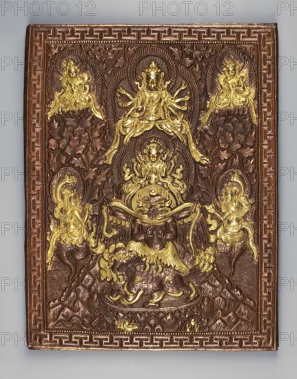 Garuda surrounded by other Buddhist deities; inscriptions; snakes; Kalachakra symbol; sculpture plaque, height 34.6 cm, width 28 cm; 18th–19th century; maker, Himalayan/Tibetan Buddhist art Tibet/Mongolia origin?., A rectangular embossed metal panel with a decorative border surrounds a detailed relief scene featuring a group of stylized figures and ornate floral and wave motifs. The central area shows a multi-armed deity seated above a kneeling or crouching figure with wings, flanked by other seated or standing figures placed symmetrically around it. A few smaller attendant figures are positioned in the upper corners and along the sides, some seated on lotus-like bases. The relief includes flowing garments, halo-like arches behind several figures, swirling foliage and cloud patterns, and a stylized lion or mythical beast near the lower center. The surface displays metallic brown and gold tones, with the raised ornamentation highlighted in bright gold and the background and border appea...