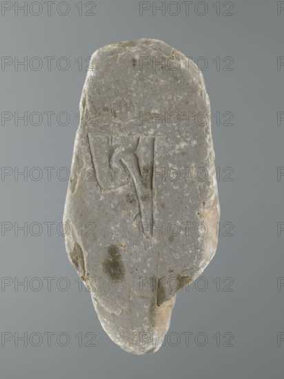 Mani stone, gift; Tibetan Buddhist ritual stone inscribed with mantras; 19th/20th century, Tibet; cult object, stone slab; height 18.3 cm, width 9.0 cm, weight 0.7 kg; Tibetan Buddhist art, Tibetan culture, Buddhism., A roughly oval stone with an irregular, weathered surface sits against a plain gray background; the stone is primarily gray with patches of lighter off-white and small areas of beige and brown, and it shows a shallow incised linear design on its face that forms angular and curved grooves; the surface has uneven texture with a few darker gray spots and subtle pitting, and the edges are chipped and rounded revealing layers of lighter beige beneath the outer gray.