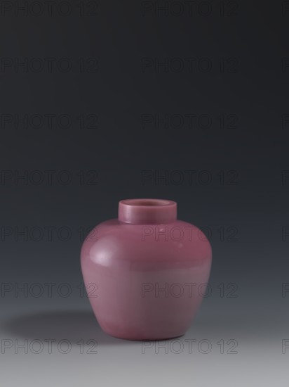 Ginger vessel, mid-19th century, China, Qing 1644–1911. Ovoid storage pot with a short collar. Porcelain vessel, height 11.5 cm, diameter 11.5 cm, weight 0.46 kg. Chinese art., A smooth rounded ceramic vase in a muted pink color sits centered on a flat surface, showing a short cylindrical neck and a glossy finish that reflects light; the background transitions from dark gray at the top to a lighter gray near the bottom, and there is a soft shadow in darker gray cast to one side.