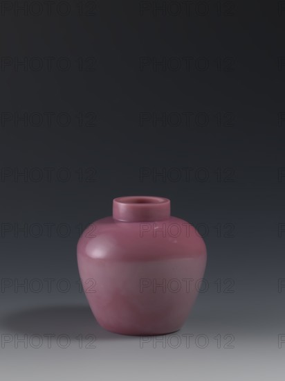 Ginger vessel, Chinese, Qing dynasty 1644–1911, mid-19th century. Ovoid storage pot with a short collar, earthenware vessel, height 11.5 cm, diameter 11.5 cm, weight 0.46 kg., A smooth, rounded ceramic vase in a muted rose color sits centered on a flat surface, showing a glossy finish with subtle highlights and soft reflections; the vase has a short cylindrical neck and a bulbous body with gentle curves, and it casts a soft shadow to one side on a gradient background that shifts from darker tones at the top to lighter gray tones near the bottom, with visible colors including rose, gray, black, and subtle white highlights.