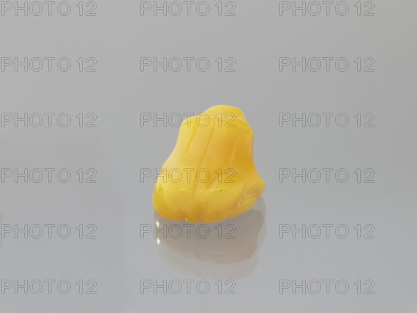 Frog, Chinese, Qing dynasty 1644–1911, 19th century; sculpture/figurine of a frog; materials unspecified; dimensions: height 1.0 cm, width 1.9 cm, depth 1.4 cm., A small smooth yellow object with rounded contours sits on a reflective gray surface, showing a soft reflection beneath it; the background is a uniform light gray.