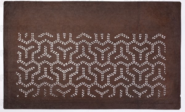 Dyeing stencil ise-katagami with the Bishamonten's armor Bishamon-kikkô motif, chuban format, geometric hexagon ornaments; stencil; Japanese; Edo 1603–1868 / Meiji 1868–1912, 2nd half of the 19th century; height 40.7 cm, width 24.7 cm., A rectangular dark brown sheet with a repeating cutout pattern across the central area, the cutouts forming interconnected Y-shaped and angular motifs that reveal white underneath; the sheet shows subtle variations of brown with slightly darker edges and a faint vertical seam near the right side, and the cutout pattern appears in a few horizontal rows creating a geometric lattice effect.