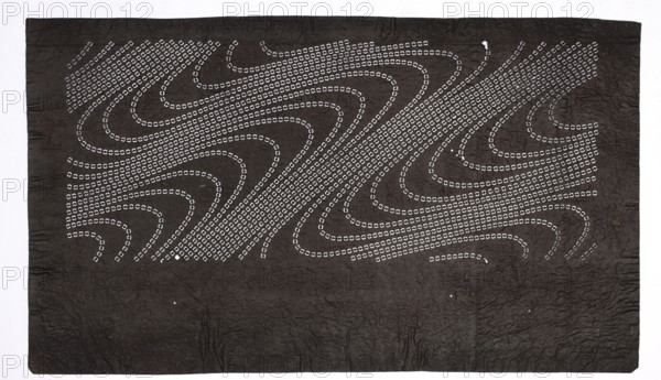 Dyeing stencil katagami with a flowing water motif ryûsui, ise-katagami stencil, chuban format; waves/water motif; Meiji period 19th/20th century, 1868–1912, Japan; stencil; height 40.0 cm, width 23.2 cm;, A large rectangular dark sheet with a textured surface fills the image, showing a group of curved, flowing dotted lines made of small light-colored marks that form wave-like patterns across the upper portion; the lower portion is mostly solid dark with subtle creases and a few tiny light specks, and the background around the sheet is a lighter pale color.