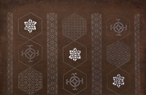 Katagami dyeing stencil with a striped motif of hemp leaves and hexagons asanoha to kikkô no shima moyô, ise-katagami, chuban format; geometric and plant patterns asanoha, kikkô. Pattern cut out on the pattern: in a striped arrangement, alternating octagons and borders with a stylised geometric and plant ornament., 2nd half 19th century Edo/Meiji period, Japan. Stencil; height 40.7 cm, width 26.0 cm., A dark brown background fills the image with a repeating vertical arrangement of hexagonal outlines formed by small white dots, creating a grid of hex shapes; inside several hexagons are intricate white decorative motifs that resemble floral or geometric rosettes, and inside others are patterned lattice designs made of white dotted lines. Between the columns of hexagons are vertical bands of repeating white dotted geometric patterns that look like flower-like star motifs. The visible colors are dark brown for the background and white for the dotted outlines and interior decorative element...