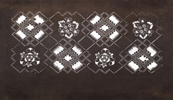 Katagami dyeing stencil with a motif of rhombuses forming crosses and plant-floral patterns hishigata jûji ni sôka moyô, Japanese, Meiji period 2nd half of the 19th century, katagami stencil, chuban format, geometric-plant patterns, flowers; stencil; height 40.7 cm, width 24.3 cm., The image shows a dark brown background with a horizontal band near the top featuring a repeating decorative pattern in white and dark brown. The pattern includes several floral-like motifs and diamond-shaped lattice elements arranged in a row, with white ornamental fills and dark brown detailing. The diamonds are connected by dashed or stitched-looking lines, and the floral motifs have leaf and petal shapes with curling flourishes. The lower portion of the image is mostly plain dark brown, while the upper patterned area contrasts with white and dark brown elements.