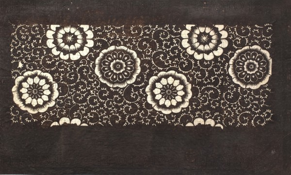 Katagami dyeing stencil with a motif of stylized flower rosettes and plant tendrils kawari kamon ni karakusa moyô, Meiji period 1868–1912, ise-katagami stencil, chuban format, karakusa pattern, floral ornaments, 19th/20th century Meiji, Japan; stencil; height 39.8 cm, width 24.0 cm., A rectangular dark brown background with a lighter central horizontal panel filled with a repeating decorative pattern; the panel contains a group of large circular floral motifs in cream and dark brown surrounded by a network of swirling vine-like tendrils in cream against the dark brown, with the lower portion of the image showing a plain dark brown area; visible colors include dark brown and cream.