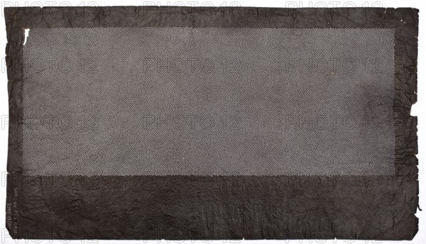Katagami dyeing stencil; pattern of overlapping circles created from a dense mesh of dots; maker, katagami stencil; geometric motifs; Japanese; Meiji period late 19th/early 20th century; Japan; stencil; height 44.3 cm, width 25.0 cm, A rectangular sheet with a textured dark border surrounding a central area filled with a dense pattern of small light dots; the border appears crinkled and uneven with torn edges, and the overall colors visible are dark brown or black for the border and light gray or off-white for the dotted central field.