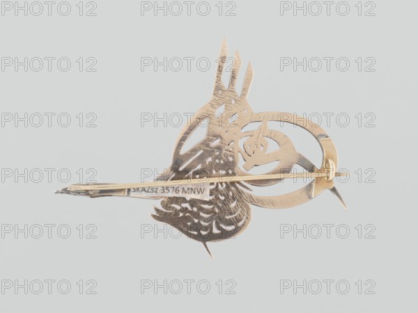 Brooch in the form of a tugra monogram of Sultan Abdulhamid II, Islamic art, Turkish culture, Ottoman dynasty 1299–1922, sultans, Abdulhamid II Ottoman Sultan; 1842–1918, tugra, ornaments, monograms, 1876–1909, Turkey, jewelry; height 4.9 cm, width 6.6 cm, thickness 0.75 cm, A metallic brooch with a stylized bird shape viewed from the back, showing cutout feather details and decorative openwork, with a thin pin and clasp mechanism crossing horizontally; the metal is a warm gold color against a pale gray background.