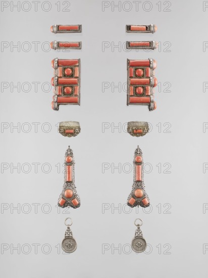 Set of braid ornaments, braid ornaments, artistic crafts, Mongolian art, jewelry, braids, women's ornaments, 19th–20th century, Mongolia, height 3 cm, width 7.8 cm, A symmetrical arrangement of decorative metal jewelry pieces set against a pale gray background, showing a pair of long vertical ornaments with ornate silver-toned filigree and coral-colored insets, a matching pair of rectangular cluster components with rounded coral-colored cabochons and horizontal coral bars, a few small cylindrical bars with coral centers and silver frames, a pair of domed half-ring components with ornate silver filigree and coral insets, and a pair of round pendant-like pieces with silver medallions hanging from small filigree loops; visible colors include silver, coral, pale gray, and a hint of warm beige on the domed components.