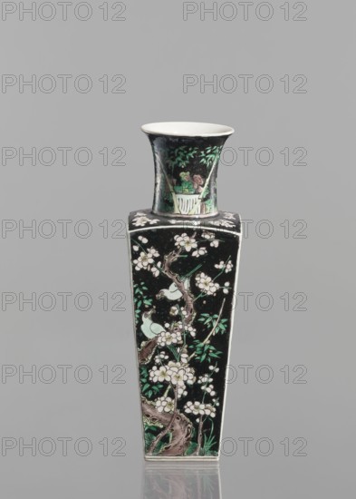 Pair of vases, Chinese, 18th century, colored porcelain famille noire, decorated with birds, plums and floral motifs; vessel, height 22.5 cm., A tall, narrow vase with a flared rim and a square body stands against a plain gray background; the vase has a black ground with painted floral branches, blossoms, and leaves in white, green, and pale pink tones, and a few small birds perched among the branches; the neck shows a scene with foliage and a pale container motif in similar green and pink colors, and the interior of the rim appears white.