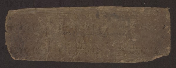 Title page of a Buddhist manuscript of the Diamond Sutra Tib. 'phags pa rdo rje gcod pa zhes bya ba bzhugs+o, unknown scribe-copyist, Buddhist art, Tibetan Buddhist art, Tibetan culture, graphic prints, manuscripts, sutra, Title page of a book in the Péch style, manuscript in the disciple script dbu can, loose pages, unnumbered. Text of the Diamond Sutra Skt. Arya Vajracchedika Prajnaparamita Sutra, translated from Sanskrit, 19th century, Tibet, manuscript, width 22.1 cm, height 7.5 cm, A worn rectangular sheet with irregular edges lies against a dark background; the sheet has a mottled surface showing creases and folds and areas of lighter and darker brown, with some faint darker smudges and a few small holes and scuffs near the edges, while the background appears nearly black.