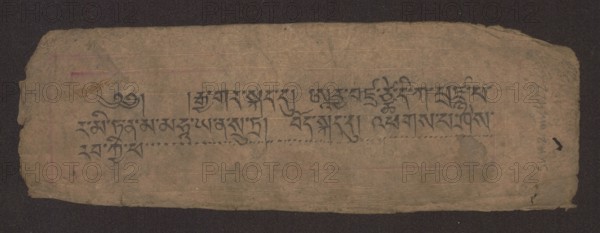 Title page of a Buddhist manuscript of the Diamond Sutra Tib. 'phags pa rdo rje gcod pa zhes bya ba bzhugs+o, unknown creator/scribe, noted, Buddhist art, Tibetan Buddhist art, Tibetan culture, graphic prints, manuscript, sutra, title page in the Péch style, manuscript in the disciple script dbu can, loose pages, unnumbered. Text of the Diamond Sutra Skt. Arya Vajracchedika Prajnaparamita Sutra, translated from Sanskrit, 19th century, Tibet, manuscript; width 22.1 cm, height 7.5 cm, A worn rectangular piece of paper with rough, torn edges placed on a dark background, showing a faded brown-beige surface with visible creases and a few small stains; a group of dark gray-black brush strokes form a horizontal band across the center, and there are faint horizontal guide lines and subtle pinkish and purplish discolorations near the left and right sides; the right edge shows a darker rounded smudge and a small black mark, while the overall texture appears fibrous and aged with variations of ta...