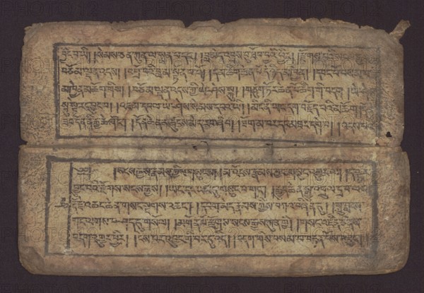 Buddhist text - Commentary on the praise of the names of Manjushri by Ga Rabjampa Kunga Yeshe Tib. 'phags pa 'jam dpal gyi mtshan yang dag par brjod pa zhugs so, noted. Buddhist art, Tibetan, graphic prints, book in Tibetan pecha style, xylographic print in student script dbu can. 26 folios, recto page numbering, first verso, 2 pages missing. Buddhist commentary on the prayer of praise in honor of the names of the bodhisattva Manjushri Tib. 'jam dpal dbyang by Ga Rabjampa Kunga Yeshe Tib. sga rab 'byams pa kun dga' ye shes. Original text from the 15th century; this copy 19th century, Tibet. Graphics; width 24.6 cm, height 8.0 cm., A horizontal view of an aged rectangular manuscript page with two rectangular text panels separated by a crease, each panel framed by a dark border and filled with rows of dark calligraphic markings; the page surface is a mottled tan and beige with areas of darker brown staining and edge wear, and the borders and script appear in dark brown to black.