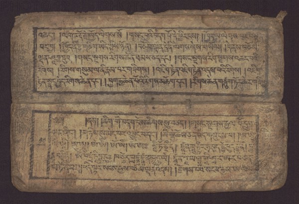 Buddhist text - Commentary on the praise of the names of Manjushri by Ga Rabjampa Kunga Yeshe Tib. 'phags pa 'jam dpal gyi mtshan yang dag par brjod pa zhugs so, unknown creator classification/graphic artist author; Buddhist art, Tibetan; graphic prints; Book in Tibetan pecha style; xylographic print in student script dbu can. 26 folios, recto page numbering, first verso, 2 pages missing. Buddhist commentary on the prayer of praise in honor of the names of the bodhisattva Manjushri Tib. 'jam dpal dbyang by Ga Rabjampa Kunga Yeshe Tib. sga rab 'byams pa kun dga' ye shes. Original text from the 15th century; object 19th century, Tibet. Graphics; width 24.6 cm, height 8.0 cm., An aged, rectangular object with a worn surface in shades of tan, beige, brown, and dark gray is shown against a dark background; it appears folded with an upper and lower panel separated by a narrow crease, each panel framed by a darker border and containing dense dark markings arranged in horizontal bands; the edg...
