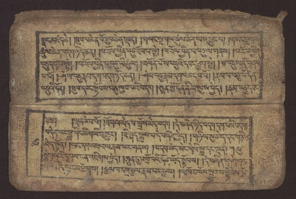 Buddhist text - Commentary on the praise of the names of Manjushri by Ga Rabjampa Kunga Yeshe Tib. 'phags pa 'jam dpal gyi mtshan yang dag par brjod pa zhugs so, unknown author, Buddhist art, Tibetan, graphic prints, book in Tibetan pecha style, xylographic print in student script dbu can. 26 folios, recto page numbering, first verso, 2 pages missing. Buddhist commentary on the prayer of praise in honor of the names of the bodhisattva Manjushri Tib. 'jam dpal dbyang by Ga Rabjampa Kunga Yeshe Tib. sga rab 'byams pa kun dga' ye shes. Original text from the 15th century; this object 19th century, Tibet. Graphics, width 24.6 cm, height 8.0 cm., A worn rectangular manuscript page lies flat against a dark background, showing two horizontal blocks of handwritten script each framed by a dark rectangular border; the page surface is a mottled tan and beige with areas of darker brown aging and smudging, and the inked script appears in a dark brown to black tone. The top edge of the page is sligh...