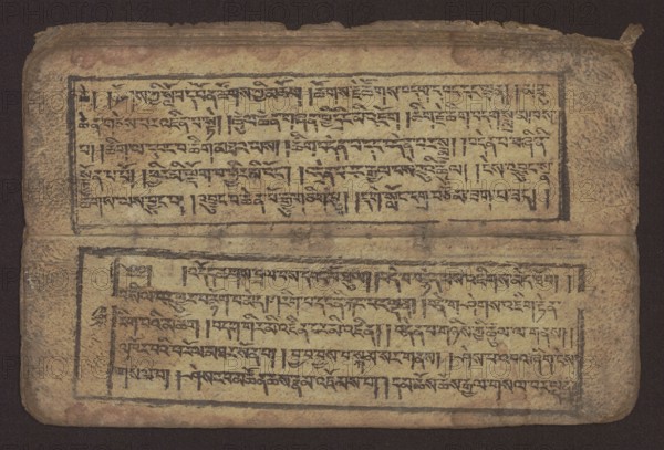 Buddhist text — Commentary on the praise of the names of Manjushri by Ga Rabjampa Kunga Yeshe Tib. 'phags pa 'jam dpal gyi mtshan yang dag par brjod pa zhugs so, author: Ga Rabjampa Kunga Yeshe Tib. sga rab 'byams pa kun dga' ye shes. Buddhist art, Tibetan; book in Tibetan pecha style; xylographic print in student script dbu can. 26 folios, recto page numbering, first verso, 2 pages missing. Buddhist commentary on the prayer of praise in honor of the names of the bodhisattva Manjushri Tib. 'jam dpal dbyang. Original text from the 15th century; this object dated 19th century, Tibet. Medium: graphics. Dimensions: width 24.6 cm, height 8.0 cm., A worn rectangular object with rounded corners lies against a dark background; its surface shows a faded beige tone with areas of darker brown and ochre staining and edge wear. The object appears divided into two horizontal sections by a faint crease, each section framed by hand-drawn dark borders. Within the framed areas there are dense, linear da...