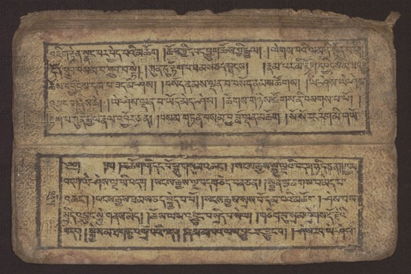 Buddhist text — Commentary on the praise of the names of Manjushri by Ga Rabjampa Kunga Yeshe Tib. 'phags pa 'jam dpal gyi mtshan yang dag par brjod pa zhugs so, Book in Tibetan pecha style, xylographic print in student script dbu can. 26 folios, recto page numbering, first verso, 2 pages missing. Buddhist commentary on the prayer of praise in honor of the names of the bodhisattva Manjushri Tib. 'jam dpal dbyang by Ga Rabjampa Kunga Yeshe Tib. sga rab 'byams pa kun dga' ye shes. Original text from the 15th century; this copy 19th century, Tibet. Graphics; width 24.6 cm, height 8.0 cm., An aged rectangular manuscript page lies flat, displaying two framed horizontal blocks of dense hand-drawn black script on a yellowed beige surface; the page edges are worn and rounded with visible creases and small tears, and the background behind the page is dark brown. The manuscript shows mottled discoloration and spotting in brown and tan tones across the surface, and the script is enclosed by thin ...
