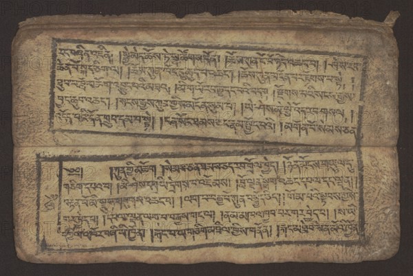 Buddhist text - Commentary on the praise of the names of Manjushri by Ga Rabjampa Kunga Yeshe Tib. 'phags pa 'jam dpal gyi mtshan yang dag par brjod pa zhugs so, unknown author/graphic artist. Buddhist art, Tibetan, graphic prints. Book in Tibetan pecha style, xylographic print in student script dbu can. 26 folios, recto page numbering, first verso, 2 pages missing. Buddhist commentary on the prayer of praise in honor of the names of the bodhisattva Manjushri Tib. 'jam dpal dbyang by Ga Rabjampa Kunga Yeshe Tib. sga rab 'byams pa kun dga' ye shes. Original text from the 15th century; this copy 19th century, Tibet. Graphics; width 24.6 cm, height 8.0 cm., A worn rectangular manuscript spread open showing two horizontal panels of dense, hand-drawn script framed by dark ink borders on aged, yellowed paper; the top and bottom panels each contain several lines of script arranged in neat rows, with visible brush or pen strokes and occasional ink blots. The paper appears creased and textured ...