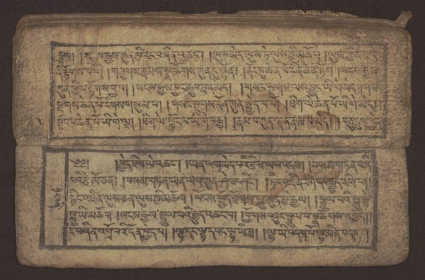 Buddhist text - Commentary on the praise of the names of Manjushri by Ga Rabjampa Kunga Yeshe Tib. 'phags pa 'jam dpal gyi mtshan yang dag par brjod pa zhugs so, unknown creator role, author. Buddhist art, Tibetan, graphic prints, book in Tibetan pecha style, xylographic print in student script dbu can. 26 folios, recto page numbering, first verso, 2 pages missing. Buddhist commentary on the prayer of praise in honor of the names of the bodhisattva Manjushri Tib. 'jam dpal dbyang by Ga Rabjampa Kunga Yeshe Tib. sga rab 'byams pa kun dga' ye shes. Original text from the 15th century; this object: 19th century, Tibet. Graphics; width 24.6 cm, height 8.0 cm., A worn rectangular manuscript spread open showing two pages with framed text blocks; the pages are aged with a yellowed beige background and darker brown stains and spotting, the writing appears in a dark brown to black ink arranged in horizontal lines within hand-drawn black border lines, and there are areas where the paper surface ...