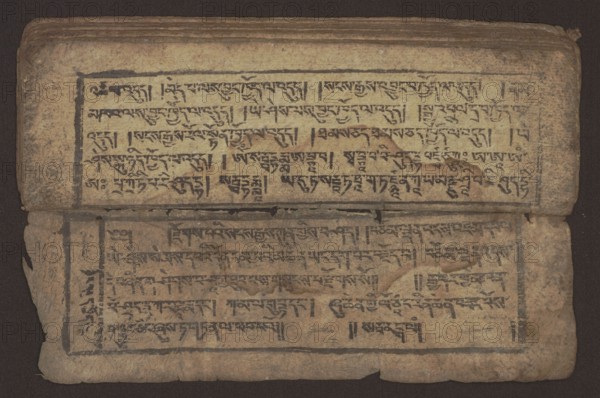 Buddhist text - Commentary on the praise of the names of Manjushri by Ga Rabjampa Kunga Yeshe Tib. 'phags pa 'jam dpal gyi mtshan yang dag par brjod pa zhugs so, unknown creator role, author. Buddhist art, Tibetan, graphic prints. Book in Tibetan pecha style, xylographic print in student script dbu can. 26 folios, recto page numbering, first verso, 2 pages missing. Buddhist commentary on the prayer of praise in honor of the names of the bodhisattva Manjushri Tib. 'jam dpal dbyang by Ga Rabjampa Kunga Yeshe Tib. sga rab 'byams pa kun dga' ye shes. Original text from the 15th century; this copy 19th century, Tibet. Graphics, width 24.6 cm, height 8.0 cm, An open, aged manuscript resting on a dark background shows two facing pages with rectangular ink borders and rows of hand-written script; the pages are worn with rough, uneven edges and small tears, and there are smudges, stains, and areas of darker discoloration across the paper. The ink used for the writing appears dark, and the paper...