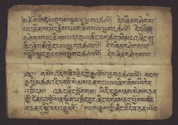 Buddhist manuscript — Penitential Text Tib. sDig bshags gser gyi zhes bya ba bzhugs+o, unknown author/scribe, Tibetan Buddhist art, Himalayan culture. Book in Tibetan pecha style, manuscript in student's script. Leaf numbering 2–22 verso, first recto, last two unnumbered. Handwritten notes folio 24 recto and verso. 19th century, Tibet. Manuscript; width 24.0 cm, height 8.1 cm., A worn, rectangular sheet with a textured beige surface showing darker aged edges and creases, divided horizontally into two main sections by a fold; each section contains rows of dark black calligraphic markings arranged in neat lines, with vertical rule lines framing the left and right margins of both sections. The paper shows small stains and smudges in brown and gray, faint spots and ink blots, and uneven discoloration with areas of lighter cream and darker tan; the top and bottom borders are slightly darker and rounded at the corners. Several ink flourishes and ornate strokes are visible along the left marg...
