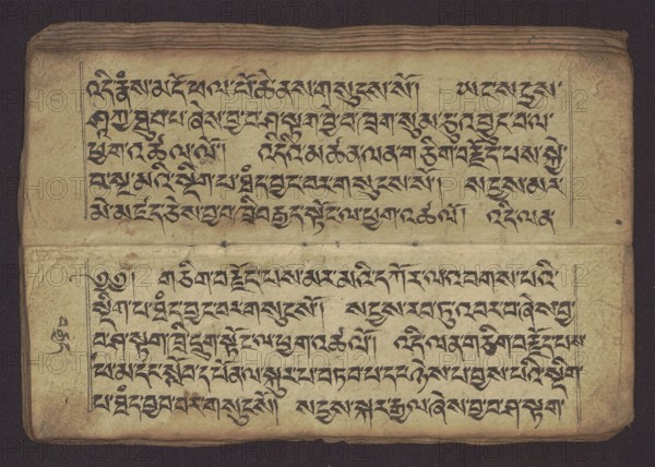 Buddhist Manuscript - Penitential Text Tib. sDig bshags gser gyi zhes bya ba bzhugs+o, unknown author/scribe-copyist, Tibetan Buddhist art, Himalayan culture, Book in Tibetan pecha style, manuscript in student's script. Leaf numbering 2-22 verso, first recto, last two unnumbered. Handwritten notes folio 24 recto and verso. 19th century, Tibet, manuscript, width 24.0 cm, height 8.1 cm, An open ancient manuscript resting on a dark background, showing two facing pages with a horizontal crease across the middle; the pages are aged with a yellowed beige tone and show darker brown stains and spots, worn edges, and slightly darker browned borders; flowing dark ink markings form dense lines across both pages; there are a few small holes and punctures near the central fold and some faint smudges and foxing across the paper; the top edge of the manuscript has several layered pages visible with darker brown ends, and a narrow ruled line frames portions of the page.