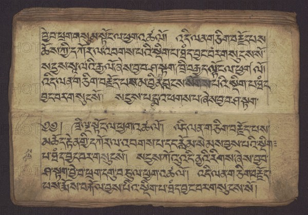 Buddhist manuscript — Penitential Text Tib. sDig bshags gser gyi zhes bya ba bzhugs+o, unknown creator scribe-copyist, student’s script, manuscript in Tibetan pecha style. Handwritten notes folio 24 recto and verso. Leaf numbering 2–22 verso, first recto, last two unnumbered. 19th century, Tibet. Manuscript; width 24.0 cm, height 8.1 cm., A worn rectangular page with a horizontal fold across the middle, showing aged beige paper with darker brown edges and slight creases; the page is filled with dense dark black calligraphic strokes arranged in horizontal lines in both the upper and lower halves, with a faint smudge of darker gray ink in the upper section; a thin ruled border is visible around the blocks of writing, and there is a narrow strip of darker brown along the outer margin; overall colors visible include beige, brown, dark black, and gray.
