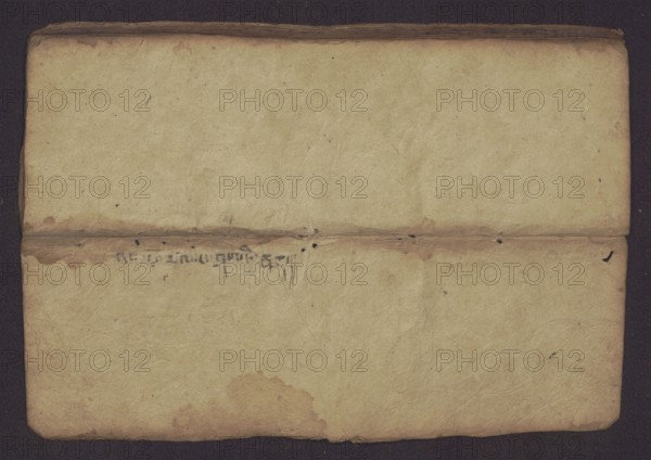 Buddhist manuscript — Penitential Text Tib. sDig bshags gser gyi zhes bya ba bzhugs+o, unknown creator/author/scribe, Tibetan Buddhist art, Himalayan culture. Book in Tibetan pecha style, manuscript in student's script. Leaf numbering 2–22 verso, first recto, last two unnumbered. Handwritten notes folio 24 recto and verso. 19th century, Tibet. Manuscript; width 24.0 cm, height 8.1 cm., A worn, folded sheet of paper lying flat against a dark background, showing a horizontal crease across the middle and gentle wrinkles and creases throughout; the paper is primarily a yellowed beige with areas of darker brown staining along the fold and edges, a few small black ink spots near the central crease, and some faint grayish specks scattered across the surface, with rounded corners and an overall aged, textured appearance.