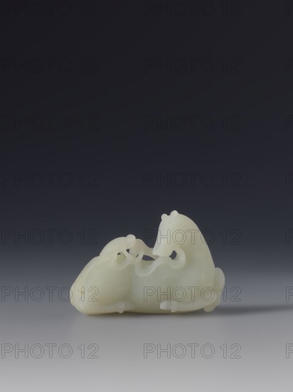 Paperweight - horse and monkey; maker, subject: horse and monkeys; materials/implements: painting implements; culture: Chinese; period: Qing 1644–1911, 18th–19th century; decoration; dimensions: height 6.6 cm, width 4.3 cm., A smooth, pale creamy-white carved object resembling two stylized animals positioned together, with one larger figure reclining and a smaller figure curving over it; the carving shows rounded forms, flowing contours, and delicate openings between parts, all resting on a flat, light-gray surface with a soft shadow beneath; the background above transitions from medium gray near the surface to a deep charcoal at the top.