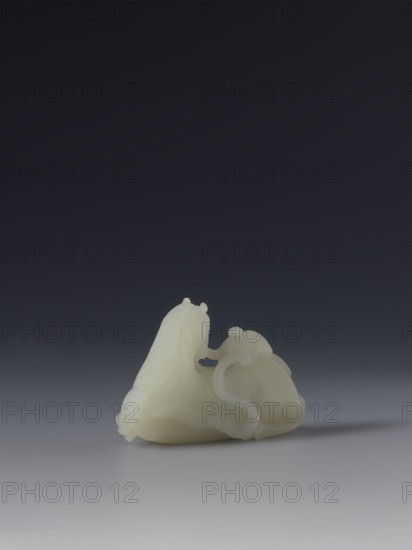 Paperweight - horse and monkey; creator, subject: horse and monkeys; materials/implements: painting implements; culture: Chinese; period: Qing 1644–1911, 18th–19th century; function: decoration; dimensions: height 6.6 cm, width 4.3 cm., A smooth pale off-white carved object rests on a reflective pale gray surface against a dark gradient background that transitions from deep charcoal to lighter gray toward the bottom; the carved piece has flowing curved forms and rounded protrusions with subtle carved linear textures on one side, and semi-translucent softer edges and curling ribbon-like elements on the other, casting a soft shadow on the surface.