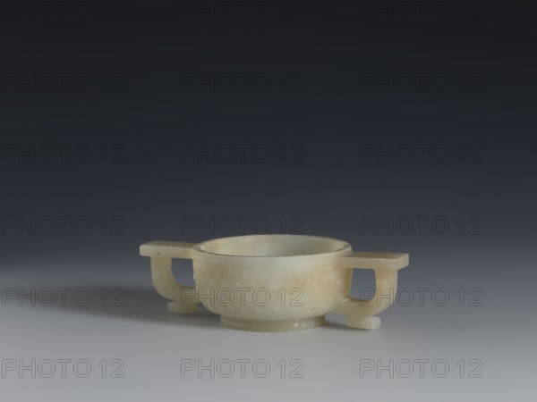 Gui-type bowl, bowls, Qing style, Chinese art, Chinese culture, vessels, ceremonial vessels, gui vessels, ruding pattern, Qing 1644–1911, the bowl's shape refers to an ancient bronze vessel, 19th century, China, vessel, height 3.0 cm, width 10.8 cm, depth 6.1 cm, A pale, translucent bowl-like object with a smooth rounded rim and a textured exterior sits centered on a smooth surface, flanked by a pair of horizontal handles that extend outward and curve down into short supports; the object shows subtle mottling and veins of warmer beige and light brown within an overall creamy white and pale greenish hue, casting a soft shadow toward the left on a gradient background that transitions from light gray near the surface to deep charcoal at the top.