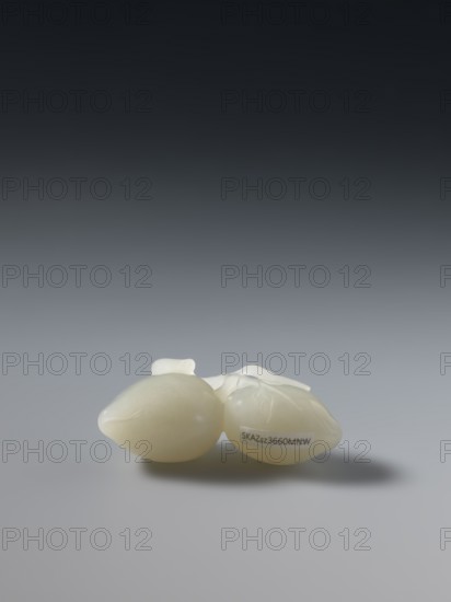 Paperweight - peaches; maker, Chinese; Chinese art; peaches iconography; Qianlong 1736–1795 style; Qing dynasty 1644–1911; date: 1736–1795; material: paperweight; dimensions: height 5.7 cm, width 3.4 cm., A group of pale off-white objects with smooth, shiny surfaces rests on a gray surface, casting a soft shadow; the background transitions from dark gray at the top to lighter gray toward the middle.