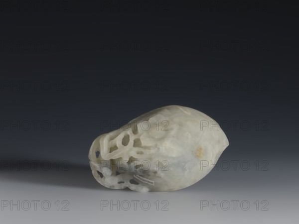 A vessel for rinsing brushes, Chinese, Qing dynasty 1644–1911, 19th century; painting implements; peaches iconography; vessel; height 3.5 cm, width 11.0 cm, depth 7.4 cm., A smooth pale stone object with a translucent, milky white and light gray surface rests on a flat surface against a dark gray to black gradient background; one side of the object shows an openwork pattern with several irregularly shaped holes and hollows, while the opposite side is more rounded and solid with subtle cloudy veining and a small area of warm yellow-brown discoloration.