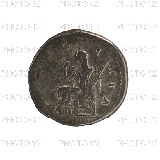 Denarius, Elagabalus 204–222; Roman emperor 218–222. Obv.: IVLIA MAESA AVG — Draped bust of Julia Maesa facing right, pearl border. Rev.: PVDICITIA — Pudicitia with a veil on her head sitting on a throne facing left, lifting the hem of her veil with her right hand and holding a scepter in her left, pearl border. 218–223, Roman Empire; Rome mint. Coin; diameter 19.5 mm, weight 3.50 g., A round metallic coin with a dark brown and gray patina showing wear and uneven surface texture; the coin features a raised, worn relief of a seated human figure facing left with an arm raised and draped clothing, and a smaller raised form near the figure that suggests an object or small stool; there are faint raised marks and irregularities around the edge of the coin and variations in the metal color including areas of darker brown, dull gray, and subtle greenish tones.