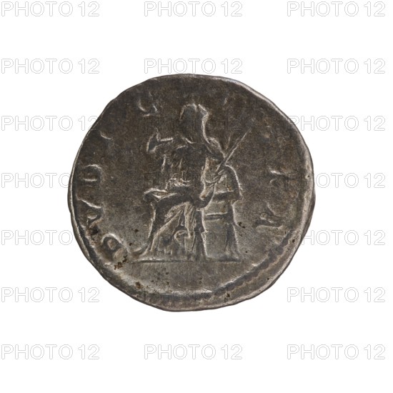 Denarius, Elagabalus 204–222; Roman emperor 218–222. Obverse: IVLIA MAESA AVG — Draped bust of Julia Maesa facing right, pearl rim. Reverse: PVDICITIA — Veiled Pudicitia seated on a throne facing left, raising the hem of her veil with her right hand and holding a scepter in her left, pearl rim. Rome; 218–223. Coin; diameter 19.5 mm, weight 3.30 g., A round, weathered coin with a dark gray metallic surface showing worn highlights of lighter gray; the coin displays the raised, worn outline of a seated human figure holding a long object, with visible contours suggesting clothing and a chair; the coin edge is slightly irregular and the surface has small pits and patches of darker discoloration, all set against a plain white background.