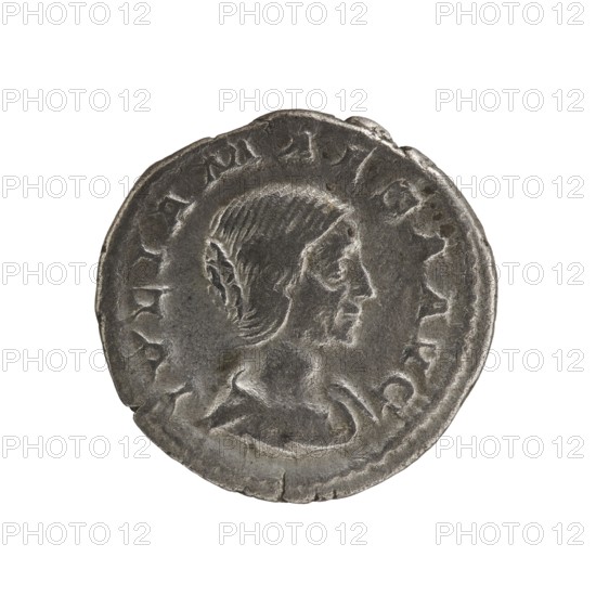 Denarius, Elagabalus 204–222; Roman emperor 218–222. Obv.: IVLIA MAESA AVG — Draped bust of Julia Maesa facing right, pearl rim. Rev.: PVDICITIA — Veiled Pudicitia sitting on a throne facing left, raising the hem of her veil with her right hand, holding a scepter in her left, pearl rim. 218–223. Rome; coin. Diameter 17.5–18.0 mm; weight 3.30 g., A round coin with a worn, textured surface showing a raised profile of a person facing right with short, combed hair and a visible ear, surrounded by a raised border with worn decorative marks; the coin appears metallic in color with shades of gray and darker gray patina and slight areas of lighter gray where the relief is higher.
