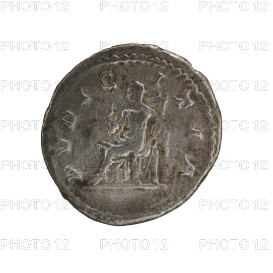 Denarius, Elagabalus 204–222; Roman emperor 218–222. Obverse: IVLIA MAESA AVG — draped bust of Julia Maesa facing right, pearl border. Reverse: PVDICITIA — veiled Pudicitia seated on a throne facing left, raising the hem of her veil with her right hand and holding a scepter in her left, pearl border. 218–223. Roman Empire. Rome. Coin, diameter 17.5–18.5 mm, weight 3.40 g., A round metallic coin with a worn, textured surface showing a raised central figure seated on a platform; the figure appears draped in cloth and there is a suggestion of another standing element nearby. The coin's edge is irregular and beaded in places, and the surface shows patches of darker and lighter tones. Visible colors include silver-gray, darker gray, and areas of brownish discoloration.