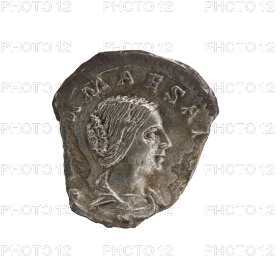 Denarius of Elagabalus reigned 218–222. Obverse: Draped bust of Julia Maesa facing right, pearl border; legend IVLIAMAESAAVG. Reverse: Veiled Pudicitia seated on a throne facing left, raising the hem of her veil with her right hand and holding a scepter in her left, pearl border; legend PVDIC ITIA. Circa 218–223 CE, Rome. Silver coin. Diameter approx. 17.0–18.5 mm; weight 1.85 g., A worn metallic object with an irregular oval shape showing a raised profile of a person's head facing right, with textured hair arranged in a braided or coiled style and a visible ear, a suggestion of clothing or drapery at the neck, and a band of raised areas near the top edge; colors visible include gray, silver, dark brown, and lighter metallic highlights.
