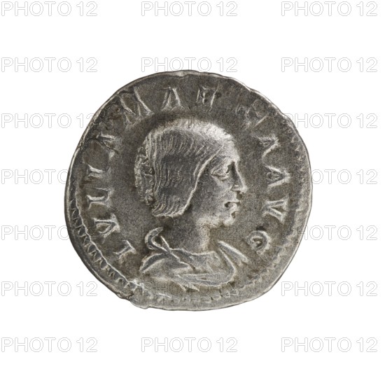 Denarius, Elagabalus 204–222; Roman emperor 218–222. Obv.: IVLIA MAESA AVG — Draped bust of Julia Maesa facing right, pearl border. Rev.: SAECVLI FELICITAS — Felicitas standing left, holding a patera above a burning altar in her right hand and a long caduceus in her left; star in right field, pearl border. Rome, 218–223. Coin; diameter c. 18.5–19.0 mm; weight 2.95 g., A circular metallic coin with a worn, textured surface showing a raised profile of a person facing right with short hair and a visible ear, shoulders, and draped clothing; the coin edge is irregular and slightly dented in places, and there is a ring of raised markings around the central portrait; visible colors include silver, gray, and darker gray tones.